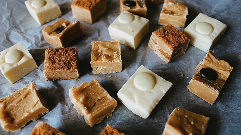 Assorted fudge pieces with various toppings on crumpled parchment paper, showcasing easy holiday dessert ideas.