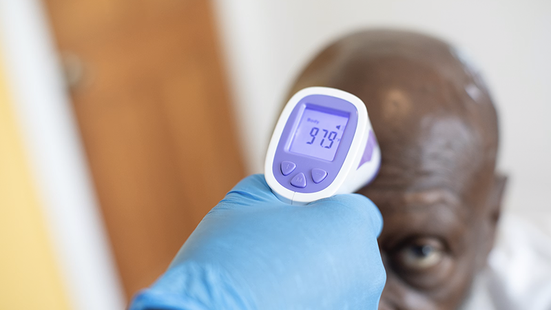 A caregiver holding a glucometer while assisting a senior with diabetes management at home.