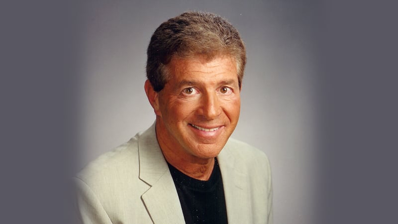 Professional headshot of Warren Pierce, a smiling middle-aged man in a light blazer, against a gradient grey background.