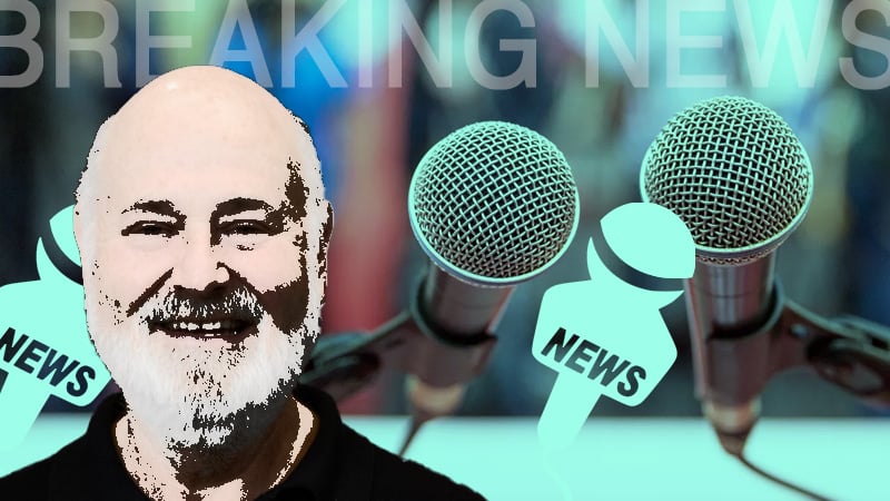 Breaking news graphic featuring a smiling man with a white beard, microphones, and news icons against a blurred background.