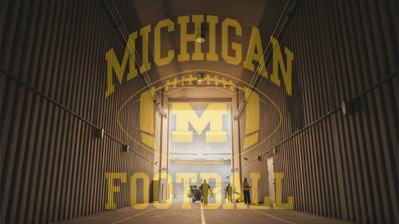 A dramatic view of Michigan Stadium tunnel with "Michigan Football" text overlay, symbolizing the team's journey amidst recent turmoil.