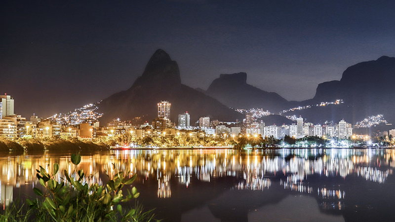 Vibrant cityscape at night with mountains and water reflecting city lights, showcasing Rio as one of the best New Year destinations.