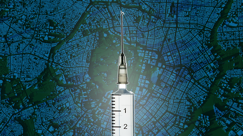 A clear medical syringe with a droplet at the needle tip, centered against a blurred dark blue and green city map background.