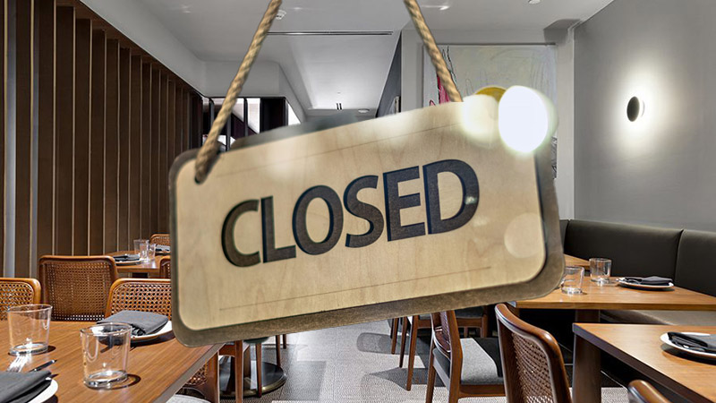A "Closed" sign hanging in a modern restaurant interior, symbolizing the struggles of D.C.'s dining industry in 2026.