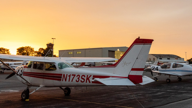 Air Race Classic planes on tarmac at sunrise with control tower in the background.
