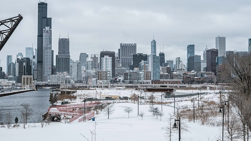 Snow-covered park with Chicago skyline featuring Willis Tower on a cloudy winter day.