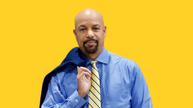 J.R. Fenwick, founder of FLipThatStock.com, wearing a blue shirt and striped tie with a yellow background.