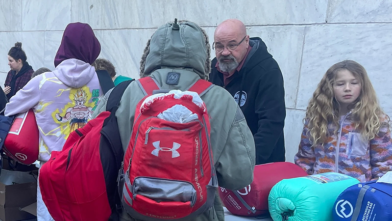 Group of people at a Kansas City shelter event distributing sleeping bags and essentials to the homeless.