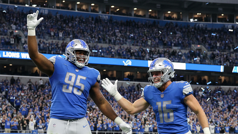 Detroit Lions players celebrating on the field after earning All-Pro honors, surrounded by confetti and cheering fans.