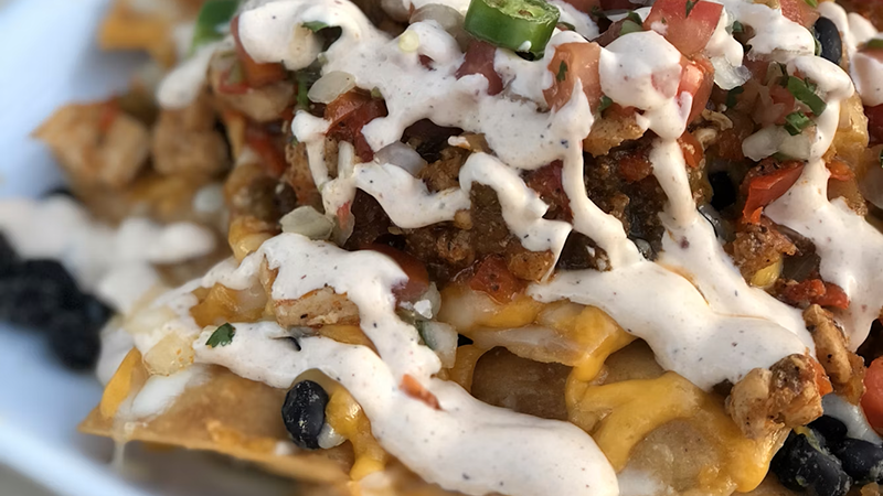 Loaded nachos with melted cheese, jalapeños, and fresh salsa, a perfect super bowl food idea.