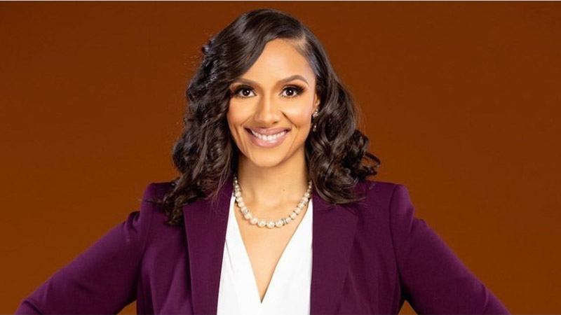 Professional headshot of Mary Sheffield, Detroit’s first female mayor, smiling confidently in a purple blazer against a brown background.