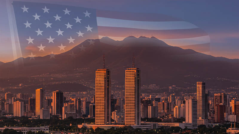 A vibrant Venezuela skyline at sunset with an American flag subtly superimposed in the background, symbolizing U.S.-Venezuela relations.