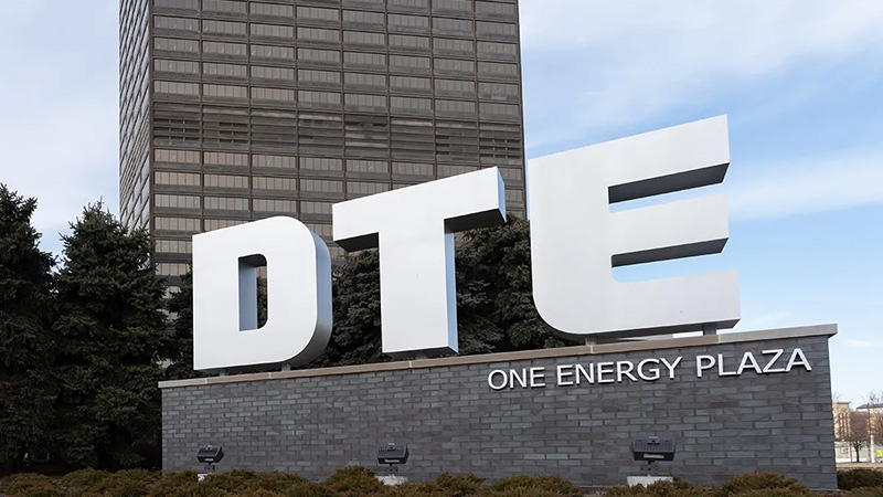 DTE Energy corporate signage at One Energy Plaza in Detroit, featuring large white 3D letters on a stone base with a skyscraper in the background.
