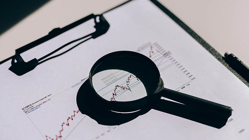 Financial chart analysis with a magnifying glass highlighting market volatility in February 2020.