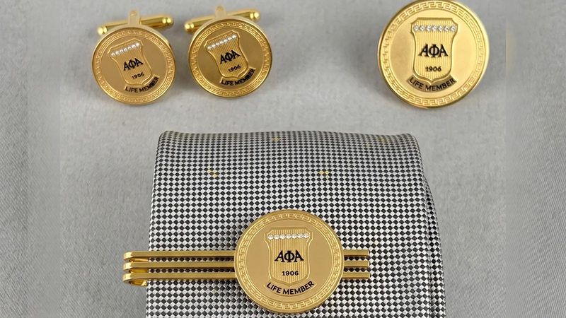 Alpha Life Member Round Gold Stone 3-Piece Set featuring cufflinks, tie bar, and lapel pin with intricate Greek key design and sparkling stones.