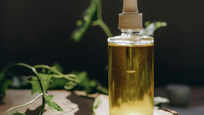 Castor oil bottle with castor beans and green leaves, highlighting its natural benefits and uses.