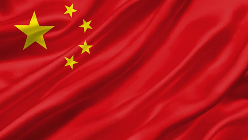 Waving Chinese flag with five yellow stars on a red background.
