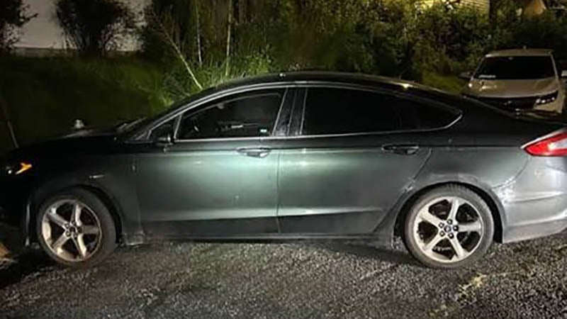 Abandoned white sedan parked on a city street after a police pursuit in St. Louis