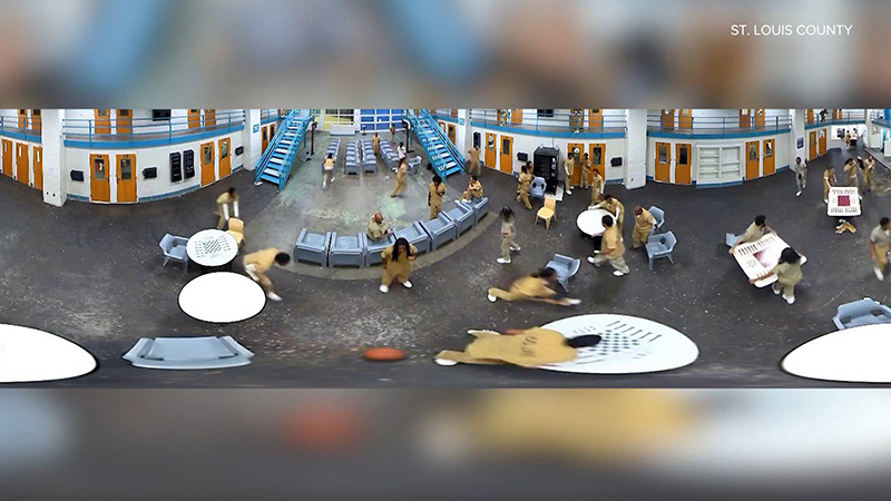 Panoramic security camera footage capturing a chaotic inmate disturbance inside a St. Louis County prison common area, showing overturned furniture and scattered individuals.