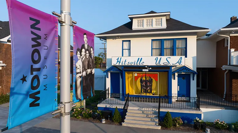 Exterior view of the Motown Museum, also known as Hitsville U.S.A., featuring its iconic blue and white facade with banners promoting Motown history.