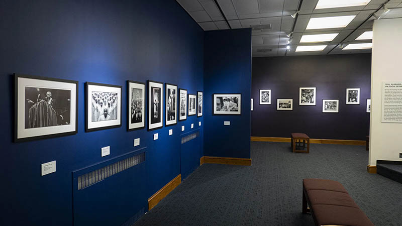 A gallery showcasing Gordon Parks’ black-and-white photographs on Black religious life, with dark blue walls and informational panels.