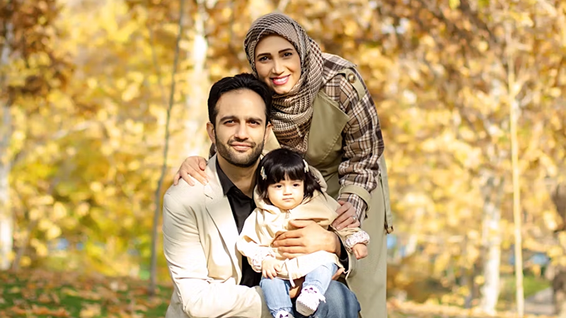 A happy family enjoying a fall day outdoors, surrounded by vibrant yellow and orange autumn leaves.