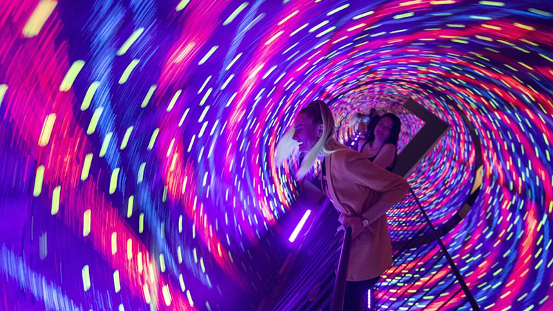 Two women enjoy a vibrant, neon-lit vortex tunnel at the Museum of Illusions in Chicago, part of the Halloween-themed events this week.