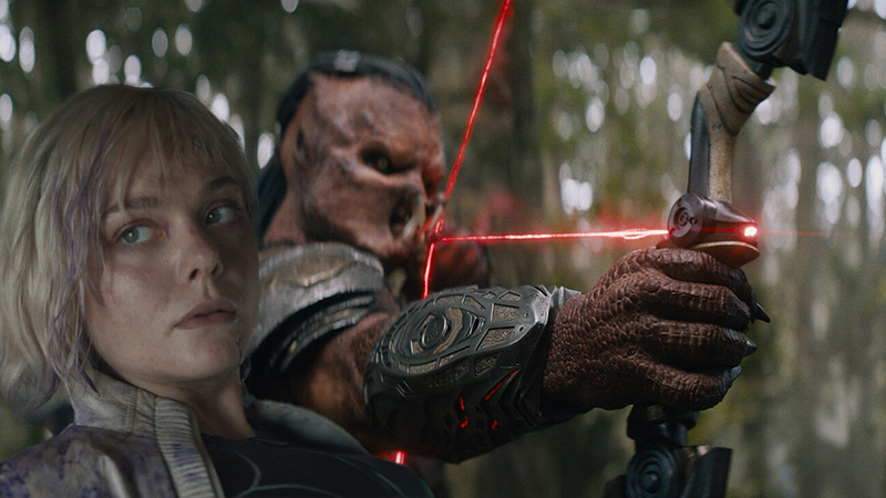 A cinematic still from Predator: Badlands featuring the rugged landscapes of Rotorua, New Zealand, and the film's lead characters, Dek and Thia.