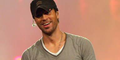 Enrique Iglesias performing live on stage in front of a packed stadium arena