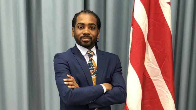 DMV regional developments spotlight D.C. Councilmember Trayon White posing in a navy suit next to the District of Columbia flag.