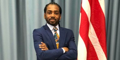 DMV regional developments spotlight D.C. Councilmember Trayon White posing in a navy suit next to the District of Columbia flag.