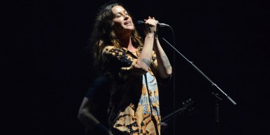 Alt-rock singer Alanis Morissette performing live with microphone under stage lights.