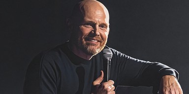 Comedian Bill Burr speaking on stage during a stand-up performance.