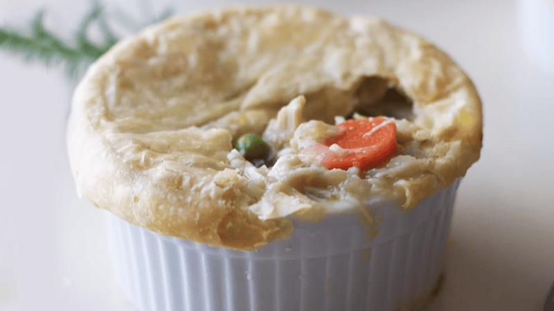 Freshly baked chicken pot pie with a flaky golden-brown pastry crust in a rustic baking dish