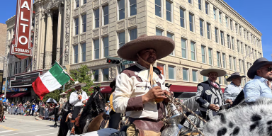 Performers in colorful traditional dress marching in the Joliet Mexican Independence Day Parade on Collins Street.
