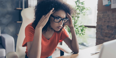 Stressed consumer reviewing credit card statements and monthly bills at a desk
