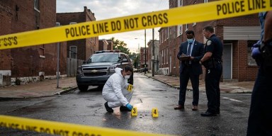 St. Louis police investigators and crime scene tape blocking off an urban street investigation.