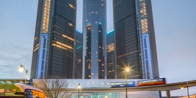 The Renaissance Center towers standing along the Detroit Riverfront under daylight.